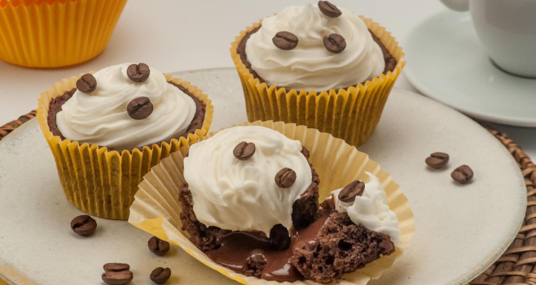 Imagem de três cupcake com chantilly e grãos de café por cima em um prato